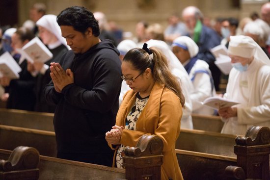 From left, John and Eunice Cruz of St. Bonaventure in Bloomington pray during the Mass.