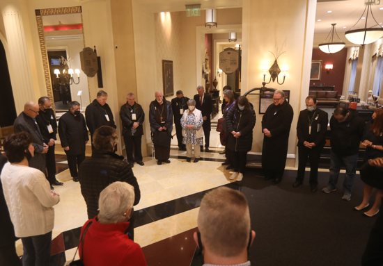 Cardinals Joseph W. Tobin of Newark, N.J., and Seán P. O'Malley of Boston, president of the Pontifical Commission for the Protection of Minors, center, join others in prayer in Baltimore before a sunrise walk to end abuse Nov. 18, 2021. They were gathered in the lobby of the hotel where the fall general assembly of the U.S. Conference of Catholic Bishops was held Nov. 15-18.