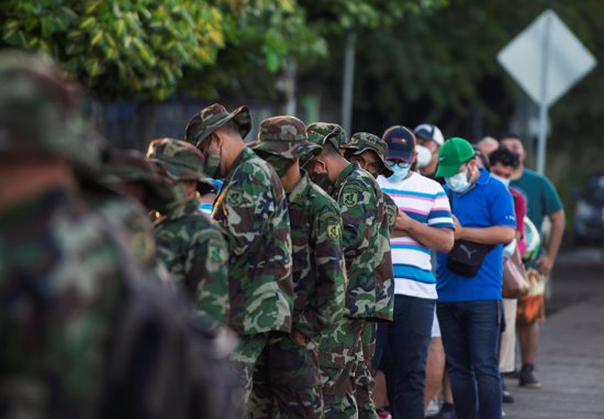 Civilians and military personnel wait in line outside a school used as polling station during the country's presidential election in Managua, Nicaragua, Nov. 7, 2021. Seven presidential candidates were disqualified and opposition figures were arrested before President Daniel Ortega won elections.