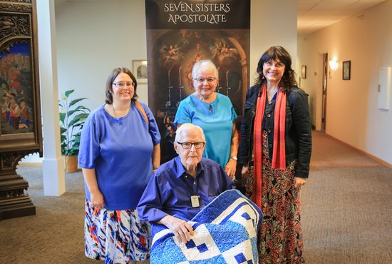 Retired Father Francis Pouliot receives a quilt at the Leo C. Byrne Residence in St. Paul Sept. 8 made by Deb Thielen of the Seven Sisters Apostolate. From left are Apostolate members Catherine Baglio and Mary Lynn Mauer, Thielen’s sister-in-law, and Janette Howe, co-founder of the Apostolate and a member of the Cathedral of St. Paul in St. Paul.
