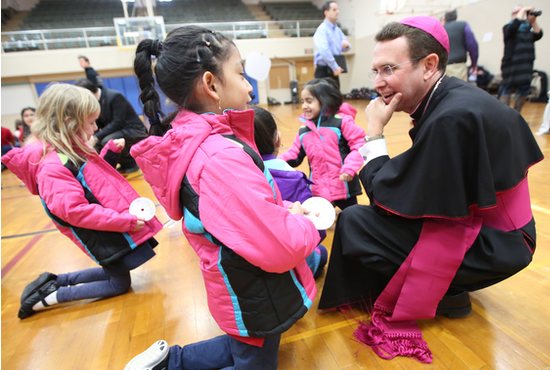 In this file photo, Bishop Andrew Cozzens talks with students at St. John Paul II Catholic School in Minneapolis Jan. 29, 2018, during a Knights of Columbus Coats for Kids donation event.