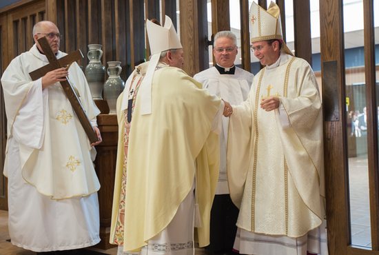 Bishop Andrew Cozzens, right, greets Archbishop Bernard Hebda at the start of his installation Mass Dec. 6 at the Cathedral of the Immaculate Conception in Crookston. At left is Father Joseph Richards, rector of the Cathedral, and at right is Father Tom Margevicius, director of the Office of Worship for the Archdiocese of St. Paul and Minneapolis. Bishop Cozzens kissed the cross held by Father Richards before continuing his procession into the church. 