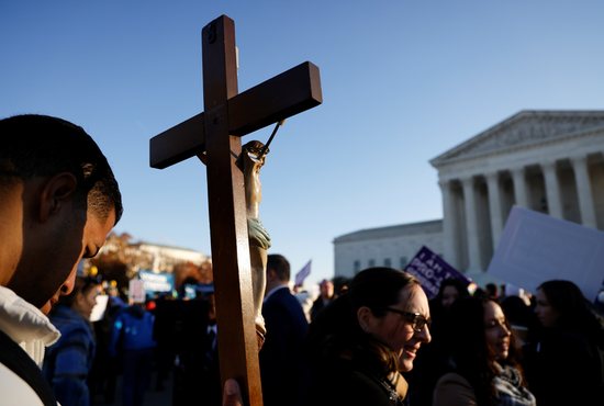 A pro-life activist holding a crucifix joins a protest outside the U.S. Supreme Court building in Washington Dec. 1, 2021, ahead of the court hearing oral arguments in the case Dobbs v. Jackson Women's Health Organization, an appeal from Mississippi to keep its ban on abortions after 15 weeks of pregnancy. 