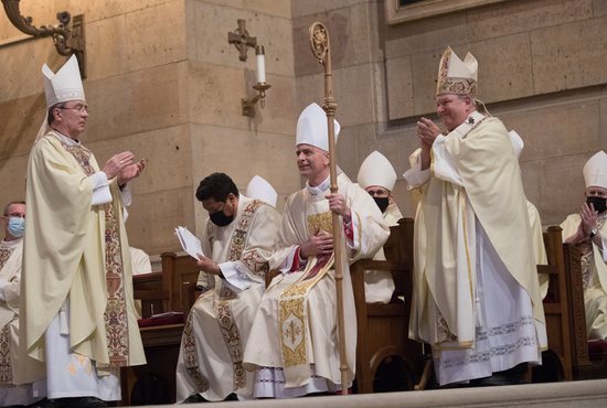 After receiving his crosier, miter and ring, newly ordained Bishop Joseph Williams receives applause from Archbishop Bernard Hebda, right, Archbishop Christophe Pierre, the apostolic nuncio to the U.S., left, and other bishops during his episcopal ordination Mass Jan. 25 at the Cathedral of St. Paul in St. Paul. At far left is Bishop Williams’ brother, Father Peter Williams, who served as one of two priest-chaplains at the Mass.