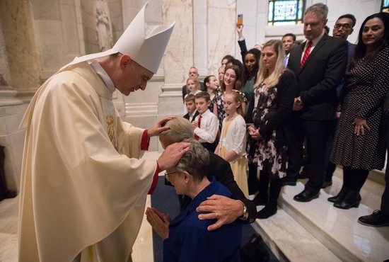 Bishop Joseph Williams gives a blessing to his parents, Dr. Gary and Mary Williams, after his ordination Mass, as other family members await their turn.
