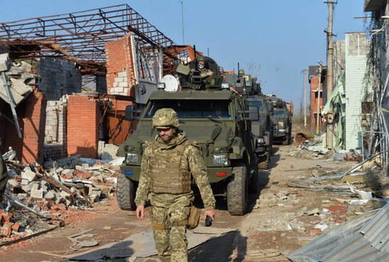 Members of the Ukrainian armed forces drive military vehicles past destroyed buildings on the line of separation from pro-Russian rebels in Shyrokyne, Ukraine, April 21, 2021.