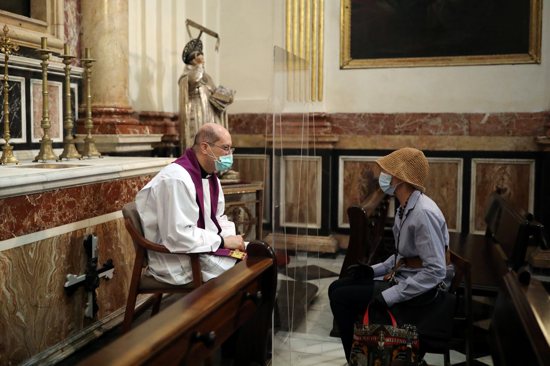 A priest hears confession inside the cathedral in Valencia, Spain, May 19, 2020, amid the first year of the coronavirus pandemic.