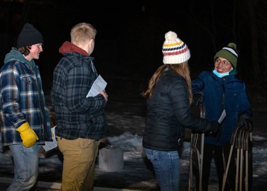 Sophomore Edgar Morente Garcia, who attends classes at St. John's University in Collegeville, Minn., and the College of St. Benedict next door in St. Joseph, Minn., hands out chairs prior to an "Ice Mass" celebrated on the frozen ice of Lake Sagatagan Feb. 20, 2022. The lake is on the St. John's campus.