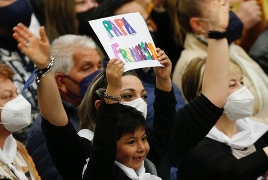 A boy holds a sign in support of Pope Francis as the pope leads his general audience in the Paul VI hall at the Vatican March 30, 2022.