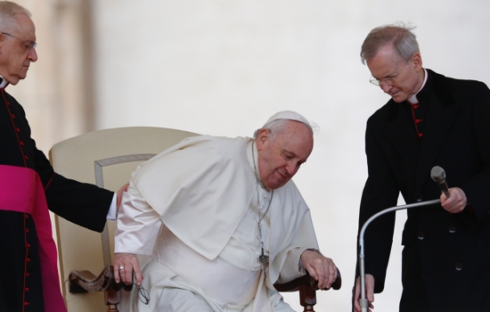 Pope Francis grimaces in pain as he gets up from his chair during the general audience in St. Peter's Square at the Vatican in this April 20, 2022, file photo. The pope told Italian newspaper Corriere della Sera that he will have knee injections for a torn ligament.