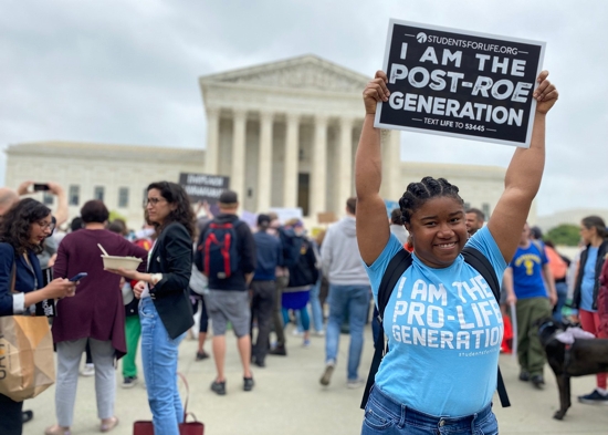 Norvilia Etienne, of Students for Life, holds a sign outside the Supreme Court of the United States May 3, 2022, the day after a draft of the court's opinion was leaked signaling that the court was leaning toward overturning Roe v. Wade.