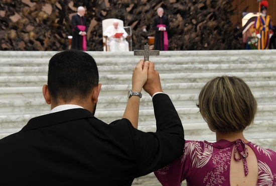 A couple hold a crucifix during an audience with members of the Neocatechumenal Way in the Paul VI hall at the Vatican June 27, 2022. The movement was preparing to send priests and 450 families on evangelization and education missions to every continent.