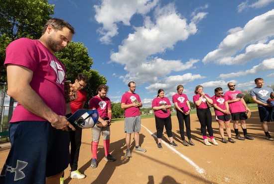 John Ondrey, left, joins his team for a pre-game prayer during Catholic Softball Group league play June 16 at Pioneer Park in Little Canada.
