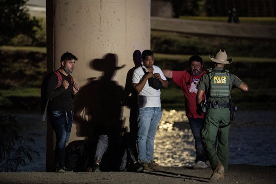 Migrants in Eagle Pass, Texas, wait to be transported by U.S. Customs and Border Protection agents after crossing the Rio Grande July 26, 2022.