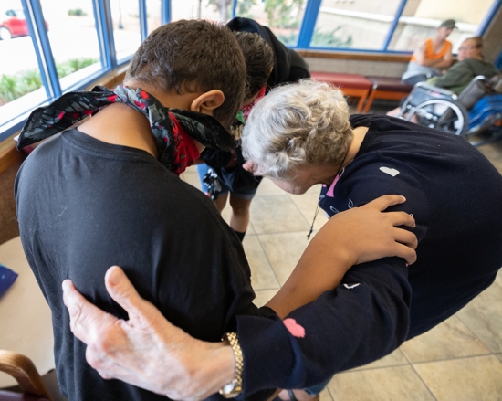 Mary Jo stops in the entryway to pray with members of a family as she exits the building following the weekly gathering.