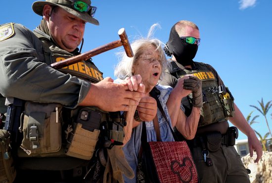 Ced Franklin is assisted by officers with the sheriff's department in Matlacha, Fla., before being evacuated Oct. 2, 2022, after Hurricane Ian caused widespread destruction.