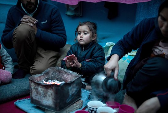 A girl is pictured in a file photo warming her hands over hot coal next to her parents inside their temporary shelter on the island of Lesbos, Greece. The European Union's Catholic bishops called government officials not to abandon families and vulnerable people this winter.