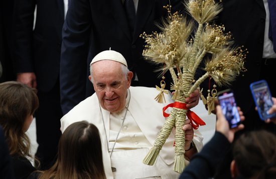 Pope Francis holds sheaves of wheat from Ukraine's harvest, a gift given to him by the wife of Ukraine's ambassador to the Holy See at the end of his general audience in the Paul VI hall at the Vatican Dec. 21, 2022.