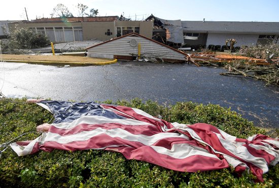 The American flag lies in the shrubs in front of the storm damaged Selma Country Club in Selma, Ala., Jan.12, 2023, after a tornado ripped through the area the previous day. A giant, swirling storm system billowing across the South Jan. 11 killed at least six people in central Alabama, the Associated Press reported.