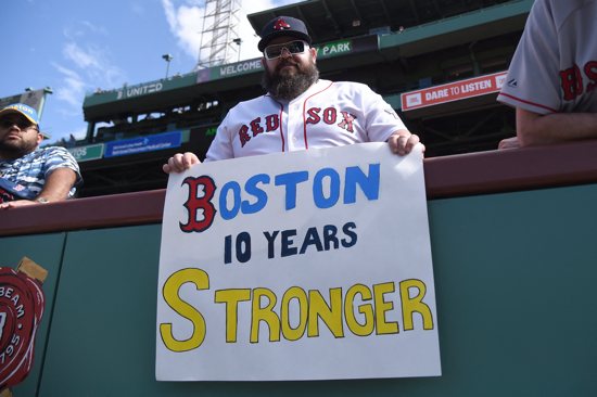 Mike Dinsmore of Salem, N.H., holds a sign commemorating the 10th anniversary of the April 15, 2013, Boston Marathon bombing prior to a game between the Boston Red Sox and Los Angeles Angels at Fenway Park.
