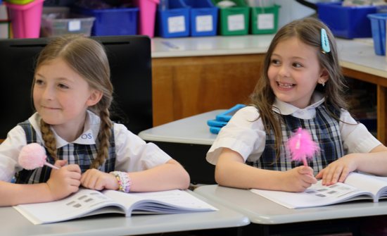 Evelyn Thallemer and Matilda Crosswy, second-grade students at Overbrook Catholic School in Nashville, Tenn., smile as they listen to their classmates May 18, 2023. The best friends raised nearly $31,000 for The Covenant School, also in Nashville, by making and selling beaded bracelets for adults and children. The bracelets feature six heart beads to represent the six victims of the March 27 mass shooting at Covenant. About $17,000 of the funds the girls raised went to Comfort Connections for a therapy dog for their peers at Covenant. A golden retriever puppy was delivered to the school May 23, and it will go through training over the summer months. How the rest of the money is used will be at the discretion of The Covenant School. 