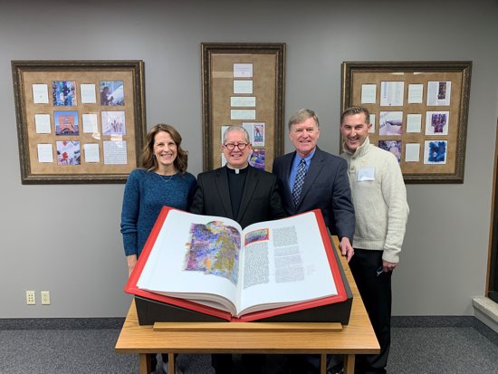 From left, Jean Nickman, a parish trustee, stands Dec. 30 with Father Erich Rutten, pastor of St. Odilia in Shoreview, Rick Storms, parish administrator and Mike Nordberg of John Roberts Company, in front of The St. John’s Bible Heritage Edition given to the parish.