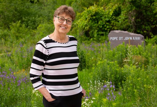 Joan Gecik stands in the natural burial area of Resurrection Cemetery in Mendota Heights, called Gate of Heaven Preserve. It contains sections with markers of saints, including St. Pope John XXIII, which is the section where she has purchased a burial plot.
