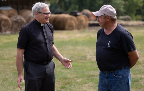 Father Stan Mader, left, pastor of St. Joseph in Waconia, talks with parishioner Ron Rademacher, who owns and operates a farm just outside of Waconia.