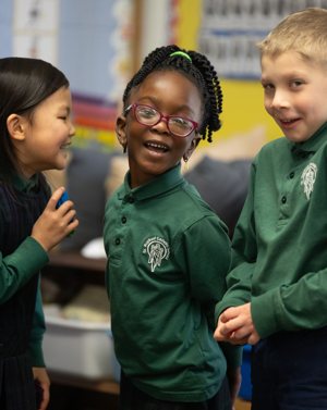 From left, kindergarten students Vivian Zhao, Bailey Tarley and Harmon Christensen share a light moment during class at St. Raphael Catholic School in Crystal.
