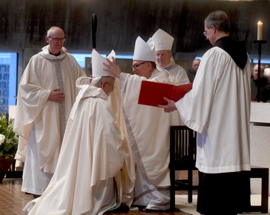 Benedictine Abbot Douglas Mullin kneels as Bishop Patrick M. Neary of St. Cloud, Minn., places the miter on his head during the rite of blessing of an abbot Jan. 28, 2024, at St. John's Abbey Church in Collegeville.