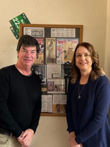 Tim Doran and Nancy Johnson flank newspaper clippings about the Catholic Athletic Association posted on the wall of an office at St. Patrick’s Guild in St. Paul.