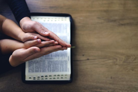 Hands praying over Bible