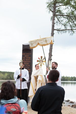 Bishop Andrew H. Cozzens of Crookston, Minn., blesses pilgrims with the Eucharist at the headwaters of the Mississippi River May 19 for the launch of the Marian Route of the National Eucharistic Pilgrimage.