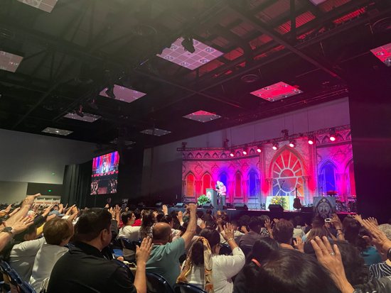Attendees at the morning Encuentro impact session raise their hands in prayer July 18.