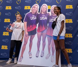 Before a July 25, 2024, pep rally at Stone Ridge School of the Sacred Heart in Bethesda, Md., students pose beside a large cutout poster of three of the school’s graduates -- Katie Ledecky (class of 2015), Phoebe Bacon (class of 2020) and Erin Gemmell (class of 2023) -- who are members of the U.S. swimming team competing in the Summer Olympics in Paris.