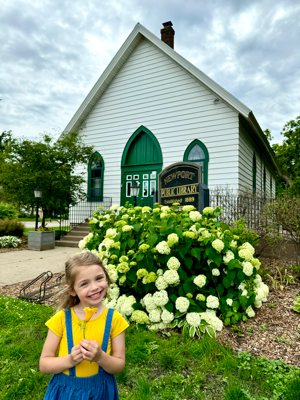 Kate Ries Capecchi, daughter of the author and member of St. Thomas Aquinas in St. Paul Park, shows off a flower in front of Newport Public Library in Newport.