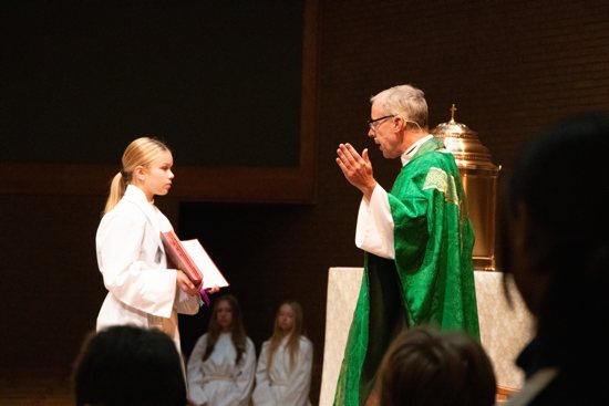 Altar server and eighth grader Emelyn Hulke assists Father Dennis Zehren, pastor of St. Vincent de Paul, during the Sept. 4 Mass.