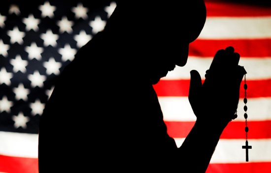 A man holding a rosary with the U.S. flag as a backdrop is silhouetted in this photo illustration.