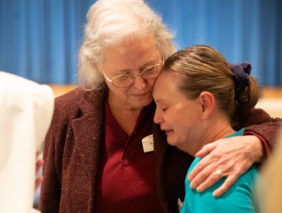 Mary Jane Lehnertz, center, a nurse at the Little Sisters of the Poor Holy Family Residence in St. Paul, hugs Krissy Klink, right, a medical assistant and certified nursing assistant Oct. 23 at the facility after a meeting in which the Little Sisters announced their plans to search for a buyer and leave the residence. 