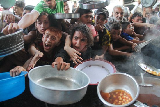 Young Palestinians gather to receive food cooked by a charity kitchen, amid the Israel-Hamas conflict, in the northern Gaza Strip Sept. 11, 2024.