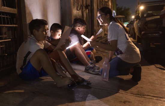 Lay missionary Josseline Montes Jiménez, right, teaches religious acclamations to members of Los Monckis, a street gang, during a May 18, 2023, visit to their hangout in Monterrey, Mexico. The Catholic Church’s annual World Mission Sunday observance, which is Oct. 20, 2024, is a day to renew the church's commitment to missionary work and to show solidarity with those who share the faith overseas.