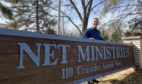 In this March 14 photo, NET Ministries President David Rinaldi stands behind the nonprofit's sign in West St. Paul. 