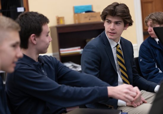 Senior Joe Spades, right, house captain, talks with ninth graders Ben Freshwater, left, and Antonio Teixeira during a morning house gathering Jan. 14. At far right is sophomore JT Fogle. 