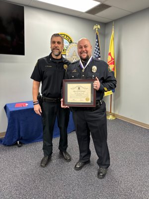 St. Paul Police Officer Charlie Redmond holds his Life Saving Award Dec. 23, with Deputy Police Chief of Operations Kurtis Hallstrom beside him.