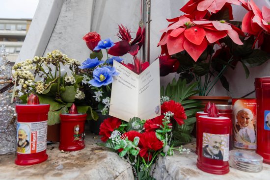 A get-well card for Pope Francis is set among flowers and votive candles at the base of a statue of St. John Paul II outside Rome's Gemelli hospital Feb. 18, 2025. Father Jim Sichko, a priest of the Diocese of Lexington, Ky, told CNS he had left the card for the pope along with a bottle of Kentucky bourbon, which was removed by someone. Father Sichko said he hoped someone took it up to the pope's room. 