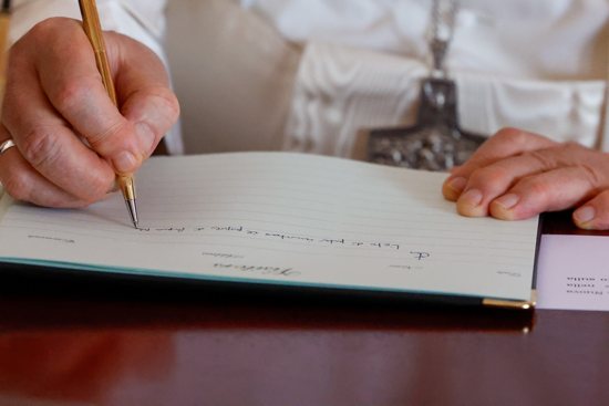 Pope Francis writes a message and signs his name in this file photo from his trip to Papua New Guinea Sept. 7, 2024.