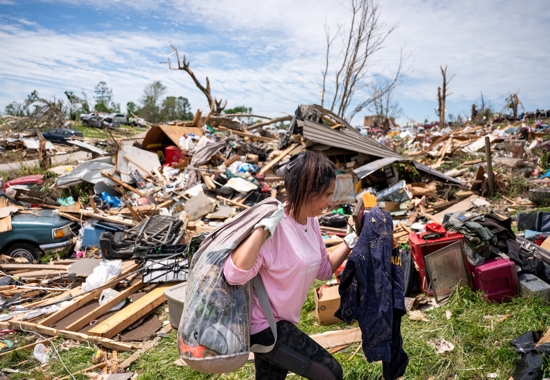 A woman carries belongings from a destroyed home in the Sunshine Hills neighborhood in London, Ky., May 18, 2025, after a series of tornadoes hit the area May 16. At least 27 people have been killed by storm systems that swept across part of the U.S. Midwest and South, with Kentucky Gov. Andy Beshear announcing May 17 that 18 of the deaths came in his state and 10 others were hospitalized in critical condition.
