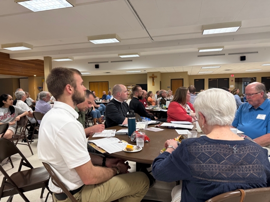In foreground, Adam Eberhard of Transfiguration in Oakdale listens during an evening of reflection for those who will participate in the Archdiocesan Synod 2025 Be My Witnesses Assembly June 7 at Cretin-Derham Hall in St. Paul.