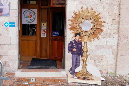 A sign featuring Blessed Carlo Acutis stands outside the Church of St. Mary Major in Assisi, Italy, April 1, 2025.