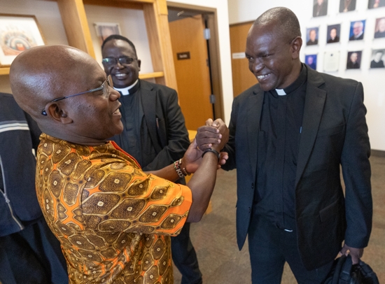 Father John Mbua Mwandi of the Diocese of Kitui, Kenya, right, greets George Mutua, left, May 11 at St. Gerard Majella in Brooklyn Park following a Mass to celebrate the 20th anniversary of a partnership between the Archdiocese of St. Paul and Minneapolis and the Diocese of Kitui. Another member of the delegation from Kitui was Father George Marete, center.